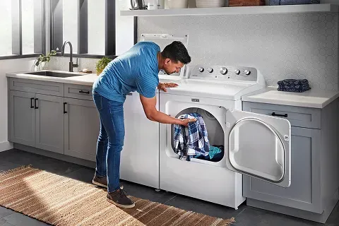 White Maytag MGD4500MW top-load gas dryer with Wrinkle Prevent feature, paired with matching washer in a home laundry setting.